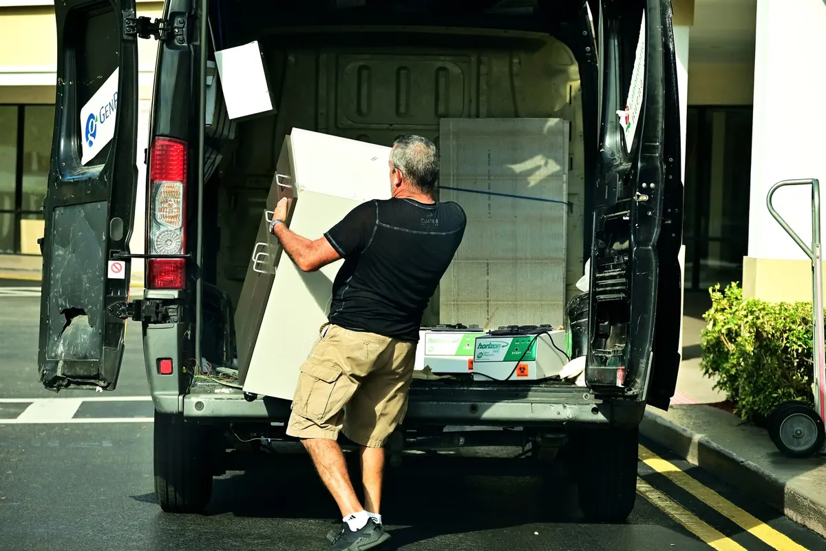 Homem carregando um móvel para dentro de uma van de frete